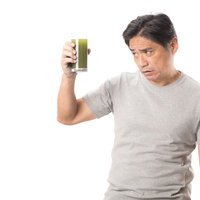 勧められた青汁を手に取る中年男性の不安な表情の写真