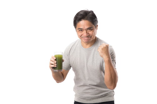 青汁を片手に勢いよくガッツをキメる中年男性