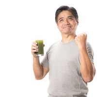 青汁を片手にガッツポーズする中年男性の健康的な笑顔の写真