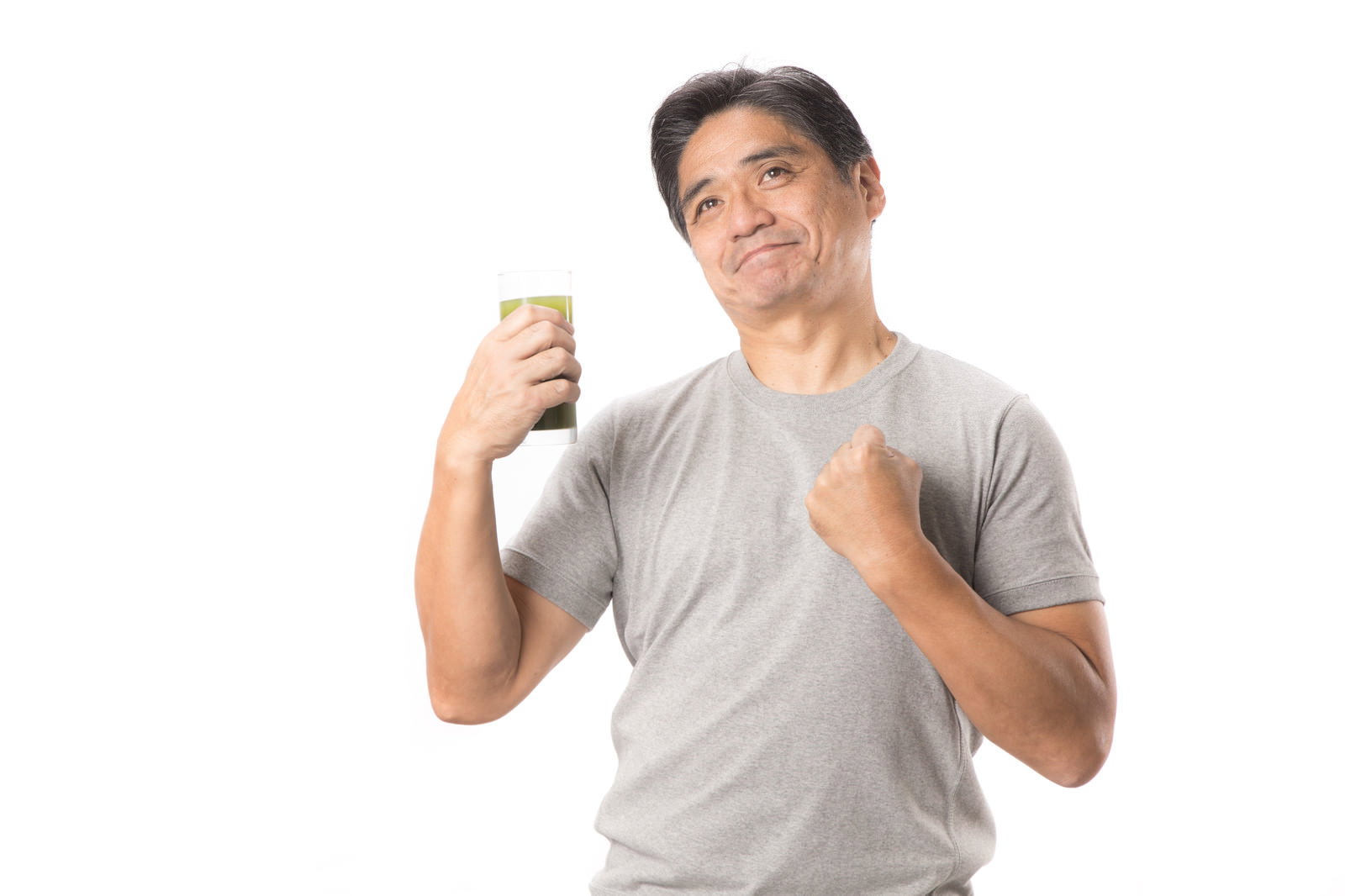 グレーTシャツの中年男性が青汁を持って笑顔でポーズ［モデル：よたか］