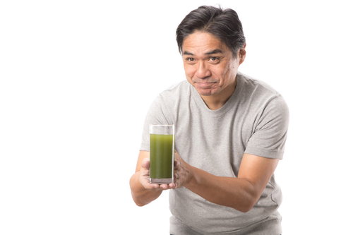 搾りたての青汁を持つ中年男性の健康的なライフスタイル