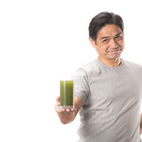 私がおすすめする青汁はこちらです（グレーのTシャツを着た中年男性）の写真