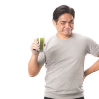 青汁を飲む中年男性の健康食品摂取シーンの写真