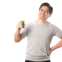 青汁を飲んでこぼれる笑顔の中年男性、健康的な生活の写真