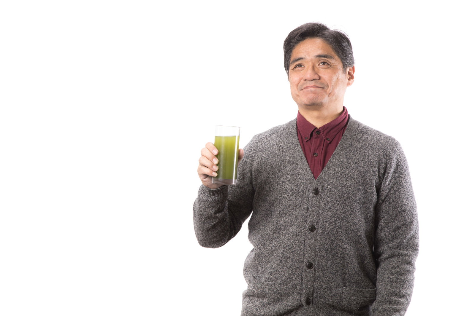 青汁を持ち上げて微笑む中年男性［モデル：よたか］