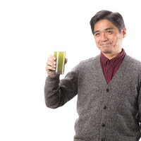 グレーのカーディガンを着た中年男性が青汁を飲んでますか？の写真