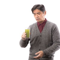 思った以上に苦い青汁を飲む中年男性の表情の写真