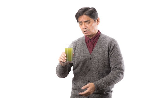 思った以上に苦い青汁を飲む中年男性の表情