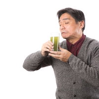 苦手な青汁をすすり飲む中年男性のお父さんの写真