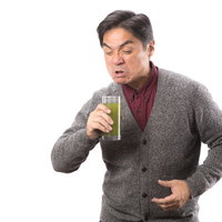 ものすごく苦いやんけ、青汁を飲む中年男性の写真