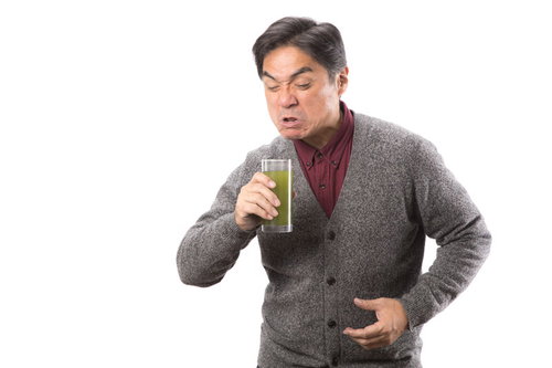 ものすごく苦いやんけ、青汁を飲む中年男性