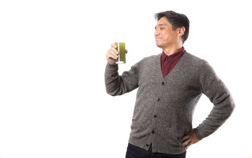 グラスの青汁を飲んでご満悦な男性の健康的な笑顔