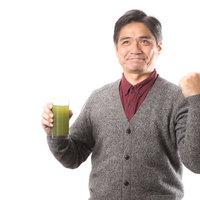 青汁を片手に親指を立てるガッツポーズの中年男性の写真