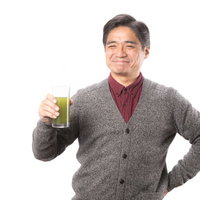 幸せそうな顔で青汁を飲み続ける中年男性のポートレートの写真