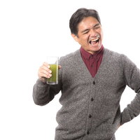 まずいけど癖になる青汁の味！飲む中年男性の写真
