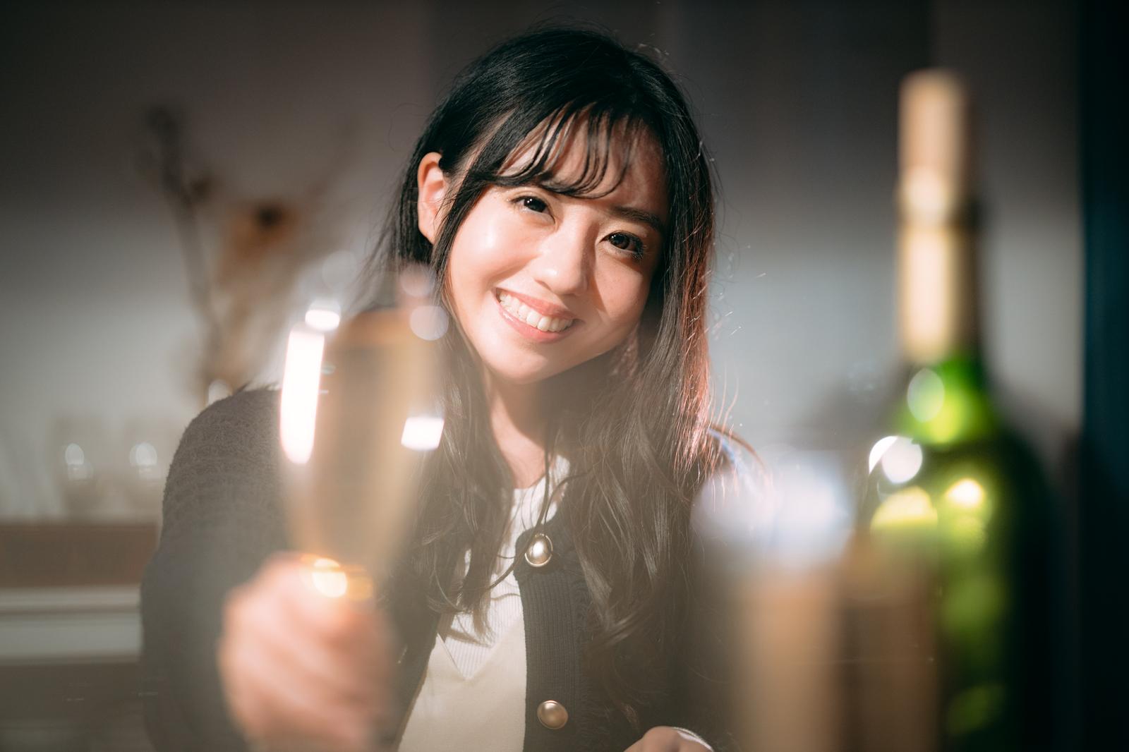 黒いジャケット姿でシャンパングラスを持ち笑顔で乾杯する女性［モデル：河村友歌］