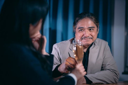 女子とお忍びデートをするイケオジがシャンパンで乾杯