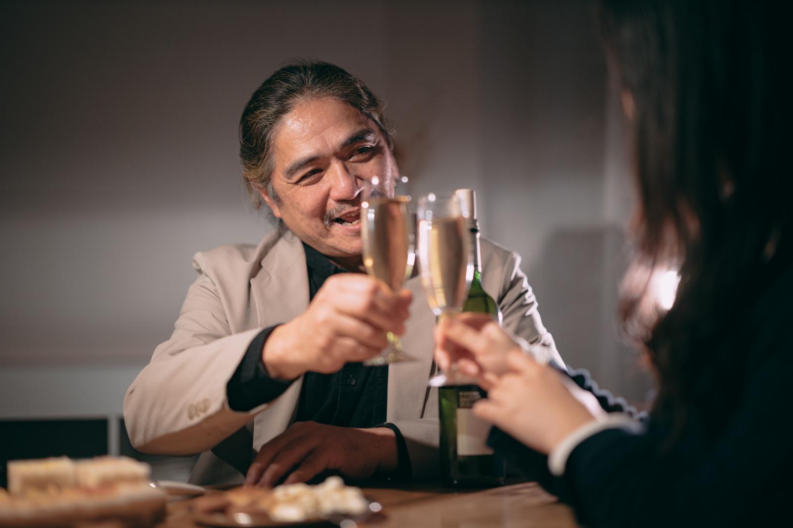 BARでシャンパンで乾杯するイケオジと女性［モデル：よたか］