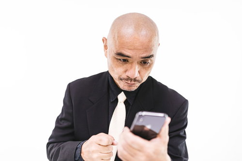 何度もスマホを見返してしまう坊主中年