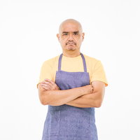 納得がいかない坊主頭の店主 青いエプロンを着た中年男性の写真
