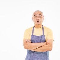 黄色いエプロン姿で驚き目を見開く坊主パパの写真