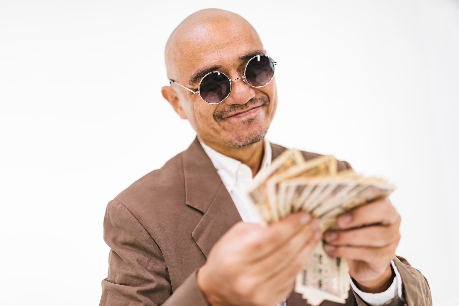 札束を手に持ってニコニコ笑顔を見せるサングラスをかけたスキンヘッドの男性［モデル：よたか］
