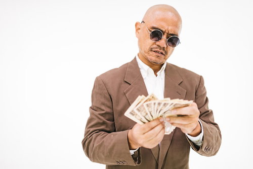 厳しい表情の取り立て人が万札を数える現金確認