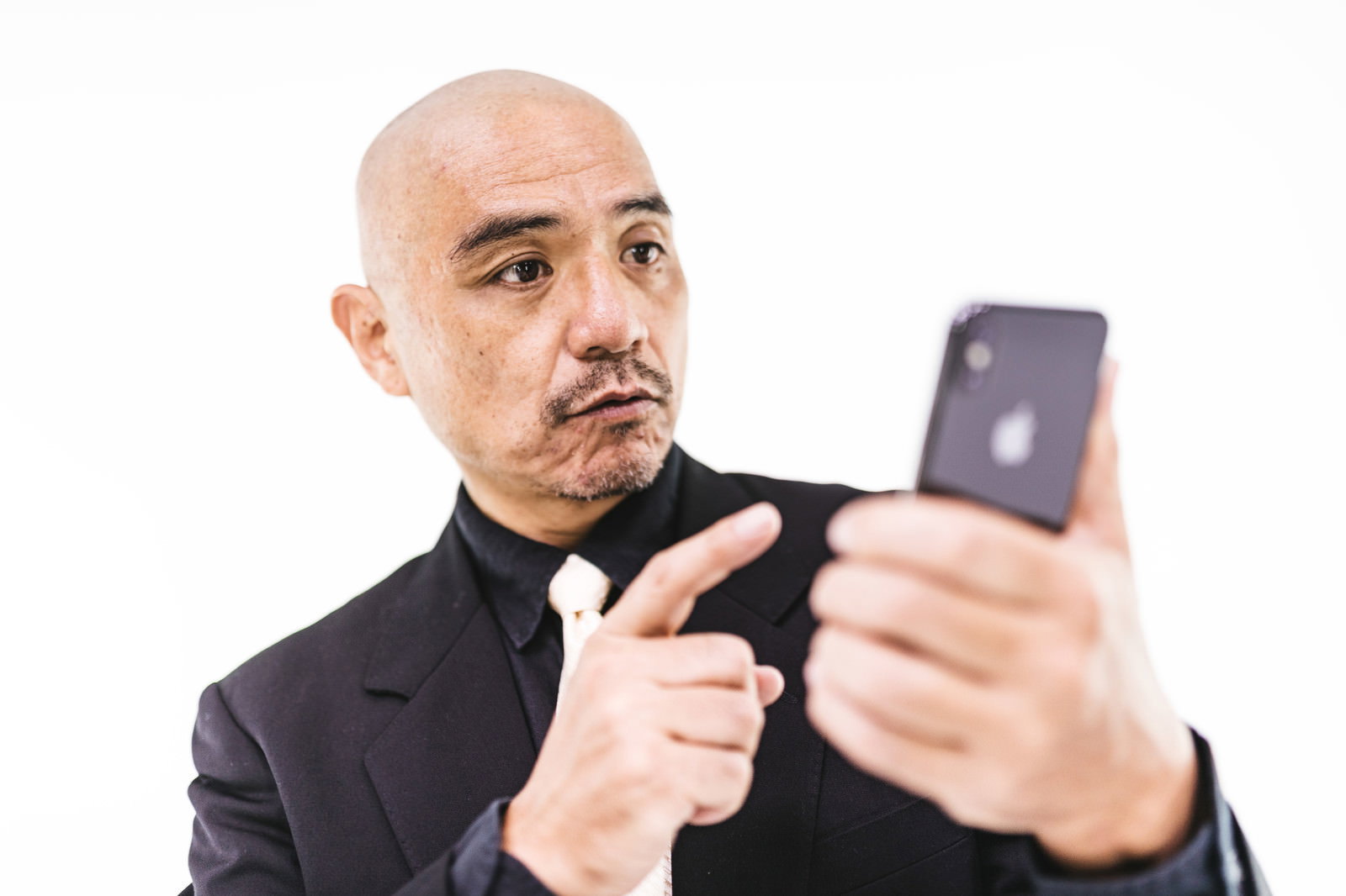スマホの画面を見つめながら操作するスキンヘッドの中年男性［モデル：よたか］