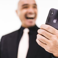 スマホを見て歓喜する強面の中年男性ビジネスマンの写真