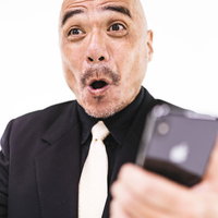 サプライズで大喜びする中年男性のスマートフォン反応の写真