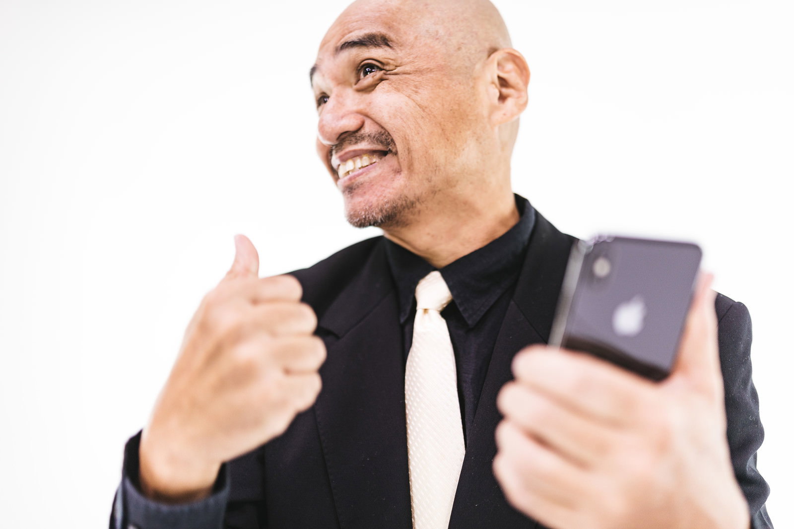 スマホを見ながら親指を立てるポーズをする坊主頭の中年男性