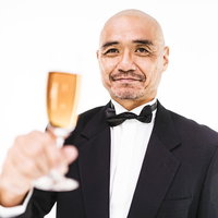 シャンパンを掲げて乾杯の挨拶をするダンディーな男性の写真