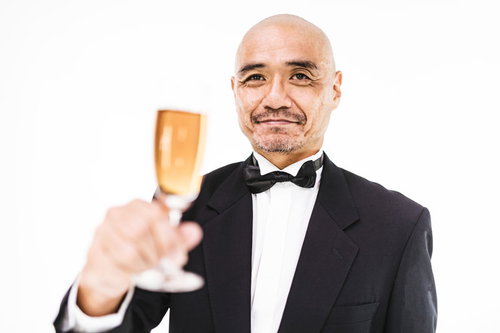 シャンパンを掲げて乾杯の挨拶をするダンディーな男性