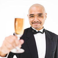 フォークで乾杯をするスキンヘッドの中年の紳士の写真
