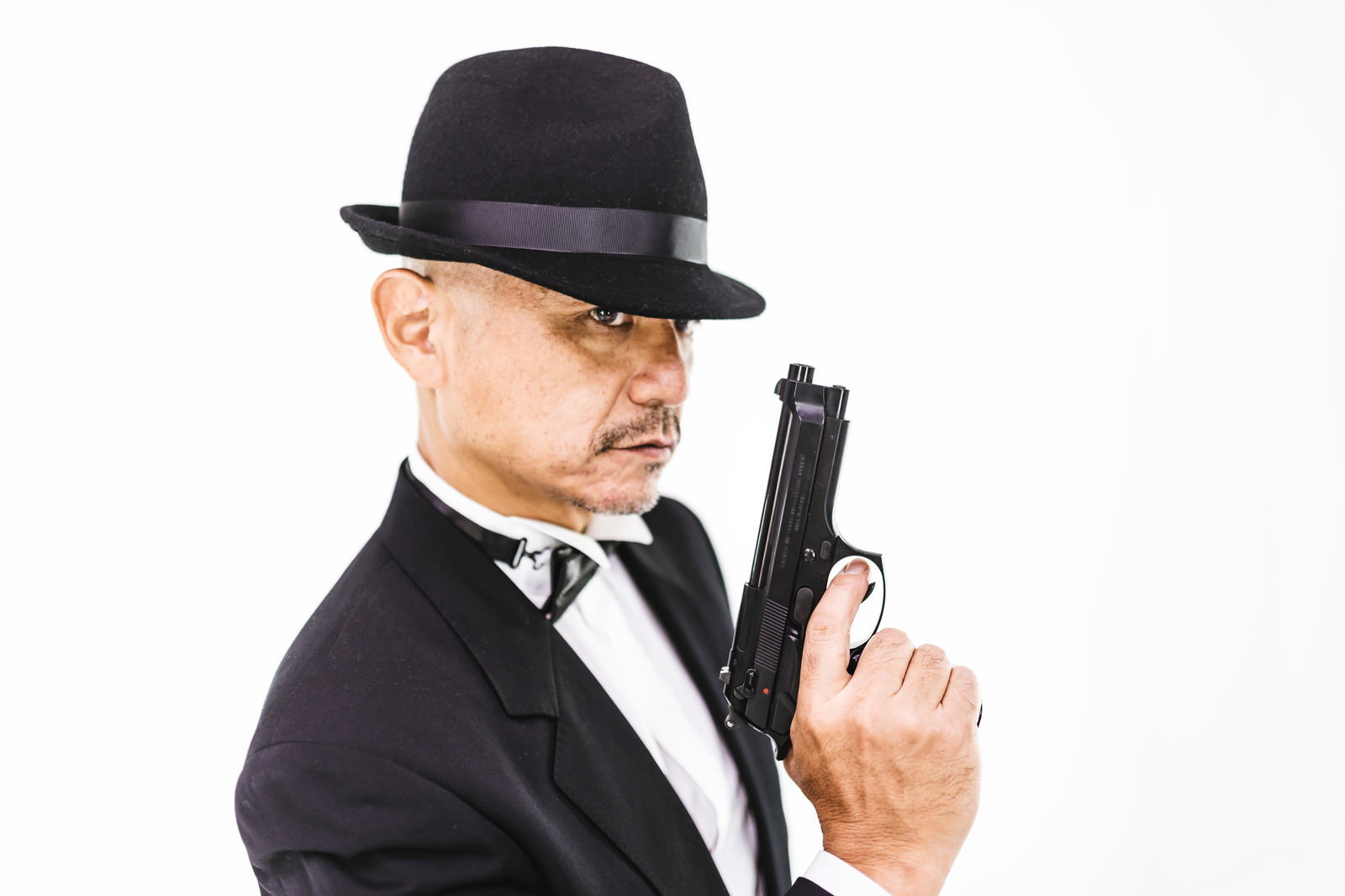 黒いスーツと帽子を着用し拳銃を構える強面の中年男性エージェント
