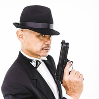 黒いスーツと帽子を着用した拳銃を持つエージェントの写真