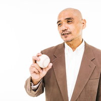 硬球を手に持ってコメントする野球解説者・監督の写真