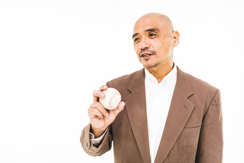 硬球を手に持ってコメントする野球解説者・監督