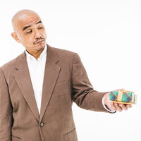 恥ずかしげにプレゼントを渡すスキンヘッドの中年男性の写真