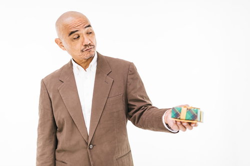 恥ずかしげにプレゼントを渡すスキンヘッドの中年男性