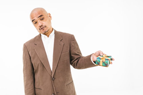 嫌々プレゼントを渡す中年男性のスキンヘッド