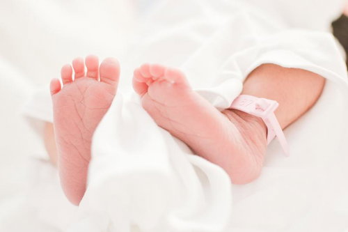 新生児の柔らかいムチムチあんよ、白い布とリボン付き