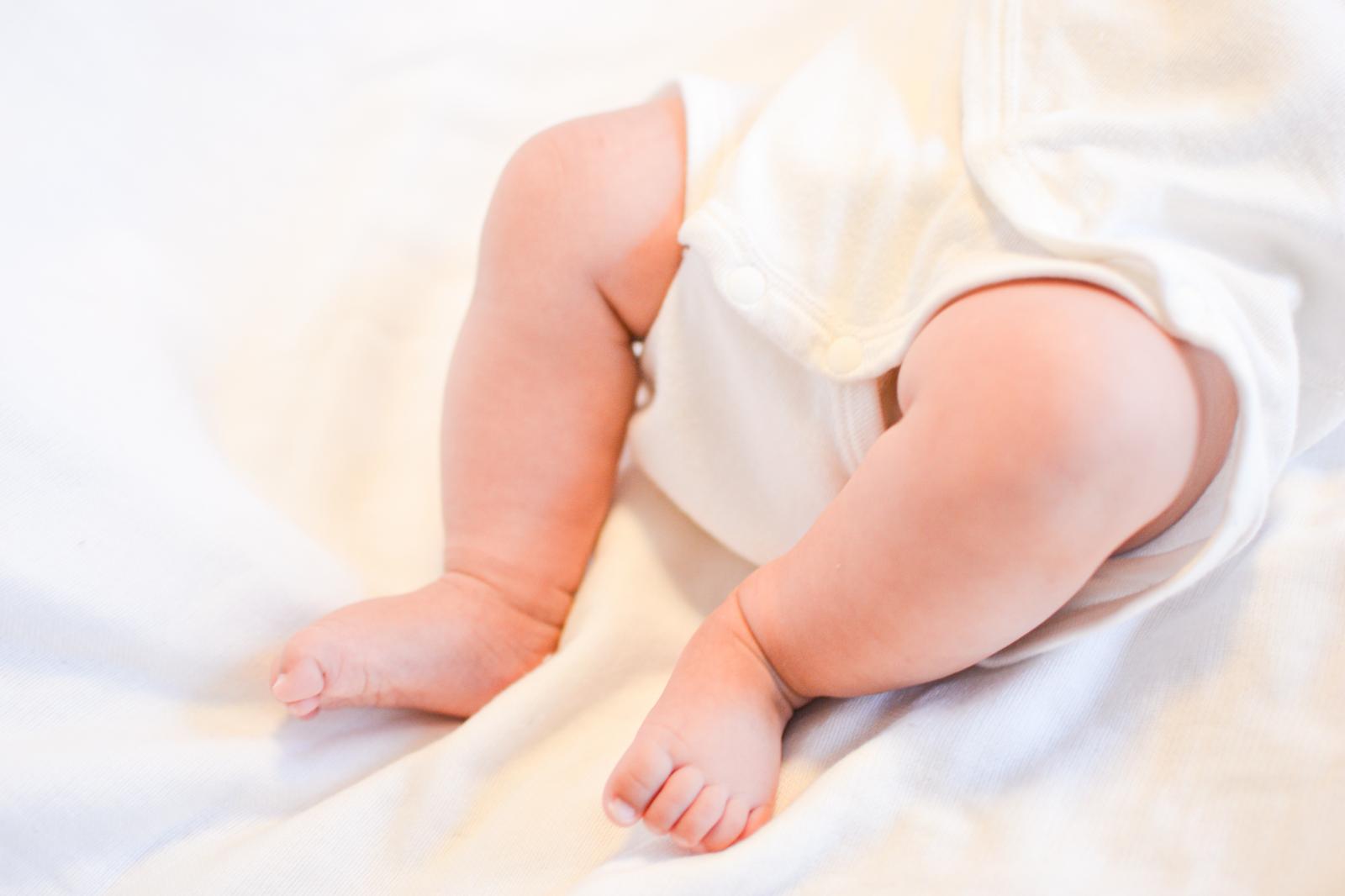 白いおくるみに包まれたムチムチの赤ちゃんの足