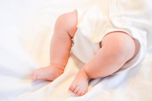 白いおくるみに包まれたムチムチの赤ちゃんの足