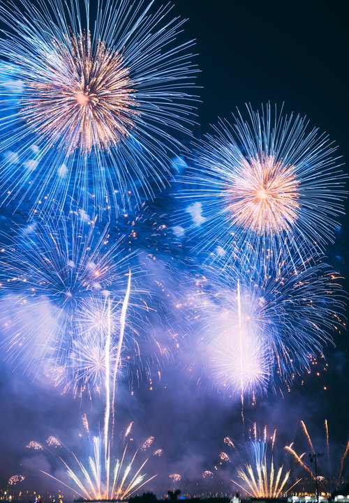 夜空に白と金色の光が放射状に広がる花火大会の打ち上げ花火