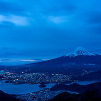 富士山と街明かりが照らす夜景、積雪の雪山と湖面の夜間風景の写真