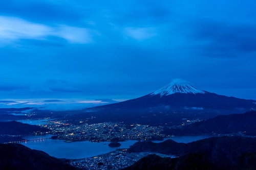 富士山と街明かりが照らす夜景、積雪の雪山と湖面の夜間風景