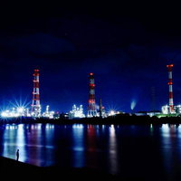 光の舞台 工場夜景の背後の物語 河川に映る夜間産業の煙突照明の写真