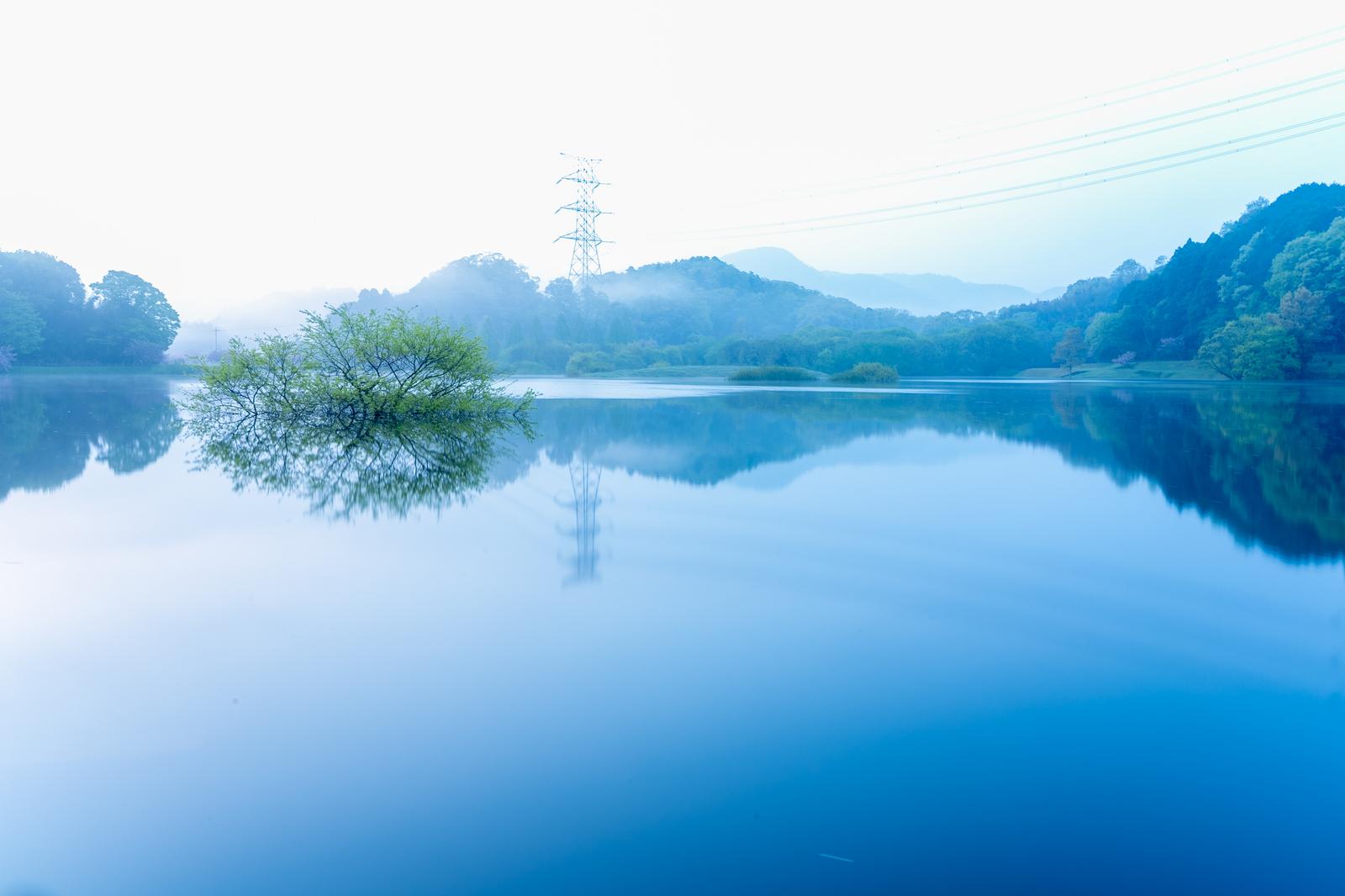 朝霧に包まれたダム湖と送電鉄塔