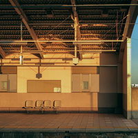 夕暮れ時の駅のホームに並ぶ椅子と金色の光の写真